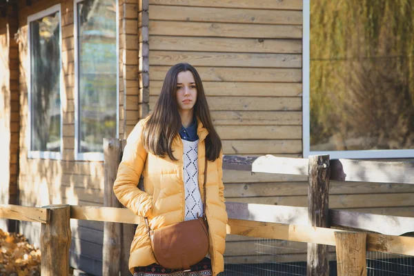 Giovane bella ragazza si trova vicino alla recinzione di legno nello zoo della città — Foto Stock