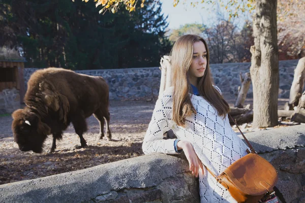 Mooi meisje staat in de buurt van de volière met bison in stad z — Stockfoto