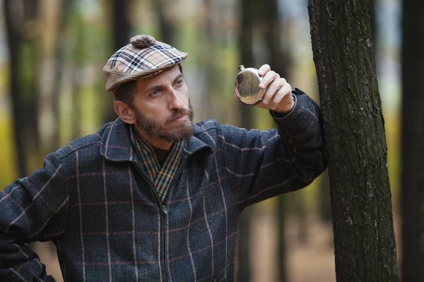 Man with a beard in scottish cap holds in hand the round flask — Stock Photo, Image