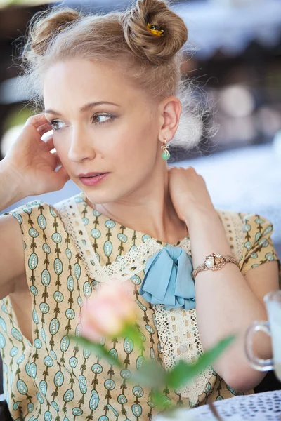 Mooie romantische blond meisje in jurk aan tafel in café — Stockfoto