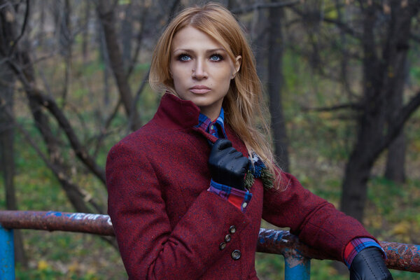 Beautiful blonde woman in jacket and leather gloves in autumn fo