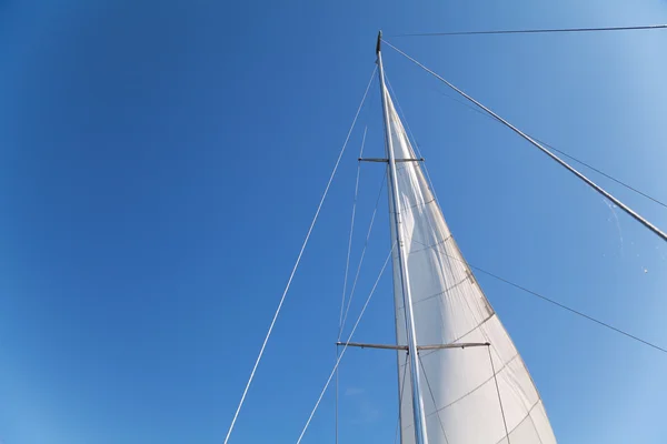 Мачта и парус яхты на голубом фоне неба — стоковое фото