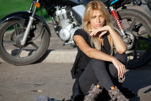 Elegante mujer rubia sentada cerca de la motocicleta — Foto de Stock