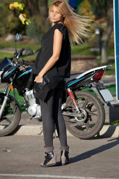 Vacker kvinna står nära motorcykel — Stockfoto