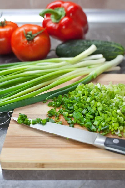 Nasekané zelené cibule a zeleniny prokládané Dřevěná deska — Stock fotografie