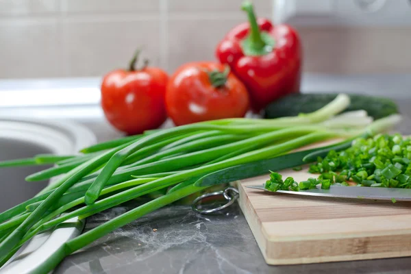 Chopped green onions and vegetables on striped wooden board — Stock Photo, Image