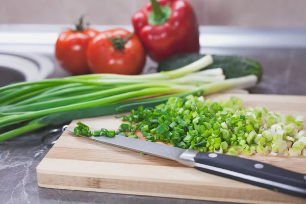 Cebollas verdes picadas y verduras sobre tabla de madera rayada —  Fotos de Stock