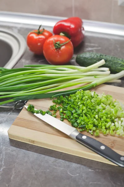 Cebollas verdes picadas y verduras sobre tabla de madera rayada —  Fotos de Stock