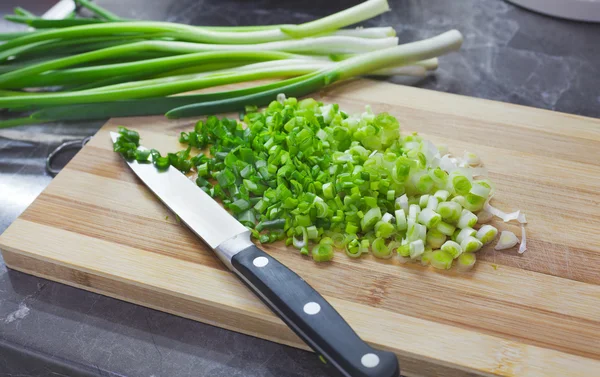 Handful of chopped green onions on striped wooden board — Stock Photo, Image