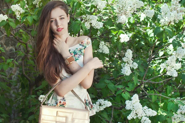 Beautiful young girl model posing near blooming lilacs at spring — Stock Photo, Image