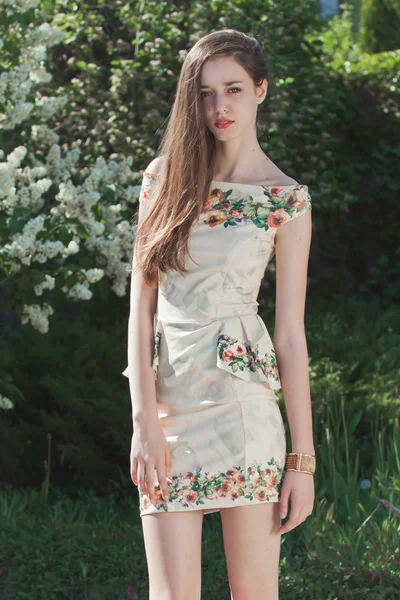 Beautiful young girl model posing near blooming lilacs at spring — Stock Photo, Image
