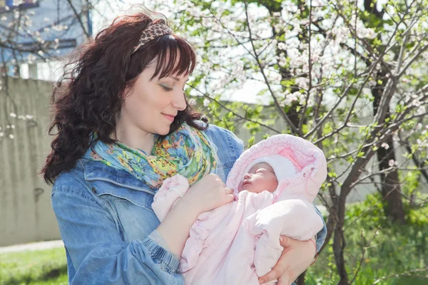 Young mother with newborn baby in outdoors at spring day — Stock Photo, Image