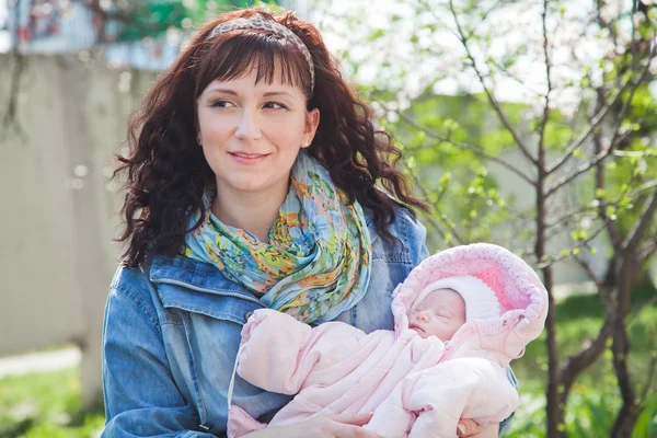 Young mother with newborn baby in outdoors at spring day — Stock Photo, Image