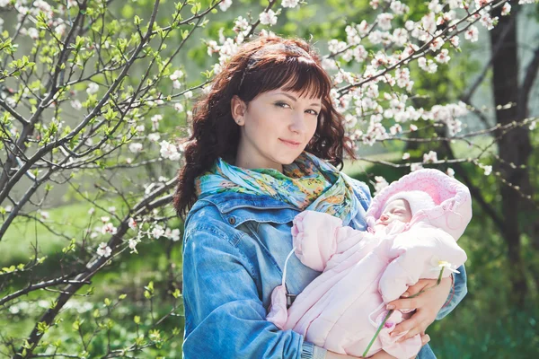 Young mother with newborn baby in outdoors at spring day — Stock Photo, Image