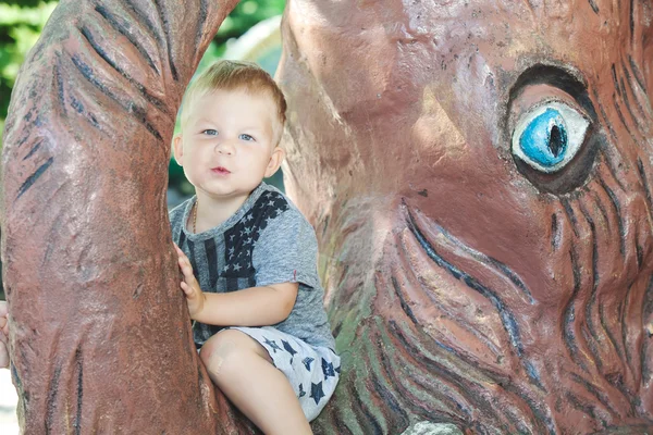 Little boy sitting on trunk of mammoth sculpture — Stock Photo, Image