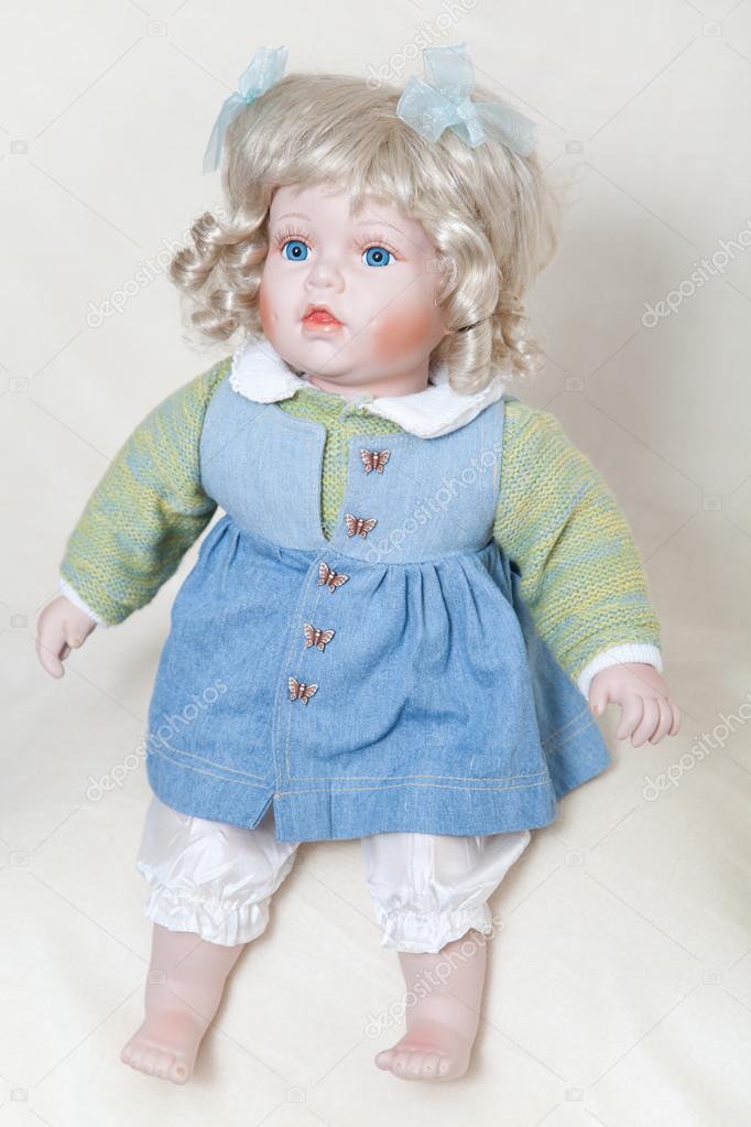 Blue-eyed girl doll sitting on soft light background