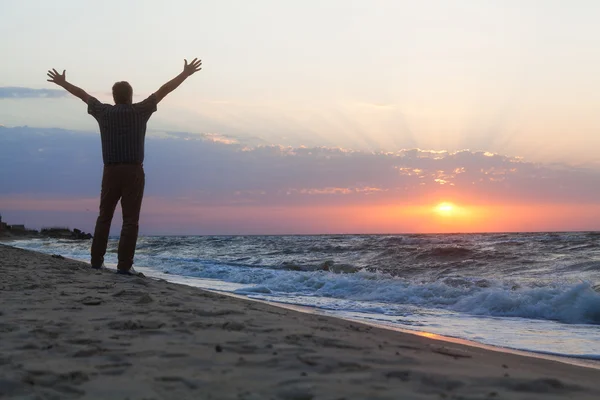 Człowiek przyjmuje z zadowoleniem wschód słońca na plaży — Zdjęcie stockowe
