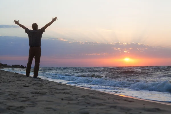 Mann begrüßt den Sonnenaufgang am Strand — Stockfoto