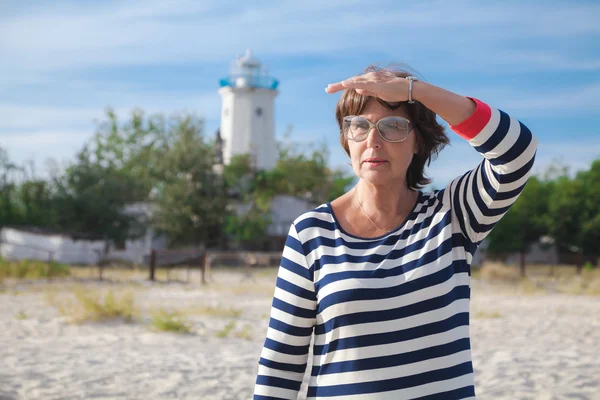 Oudere vrouw op zoek naar de afstand aan kust — Stockfoto