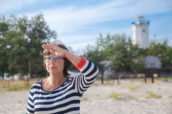 Oudere vrouw op zoek naar de afstand aan kust — Stockfoto