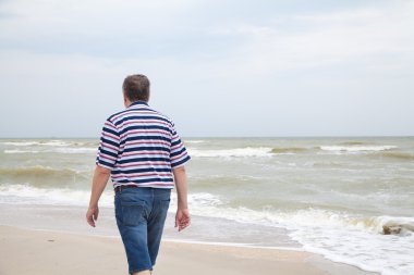 Adam deniz kumsalda yürür