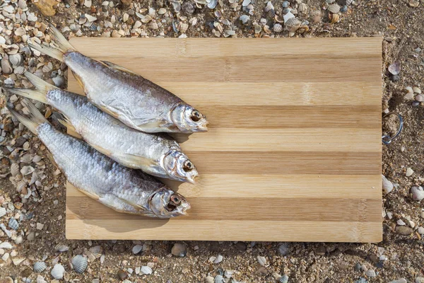 Trois poissons secs sur une planche de bois — Photo