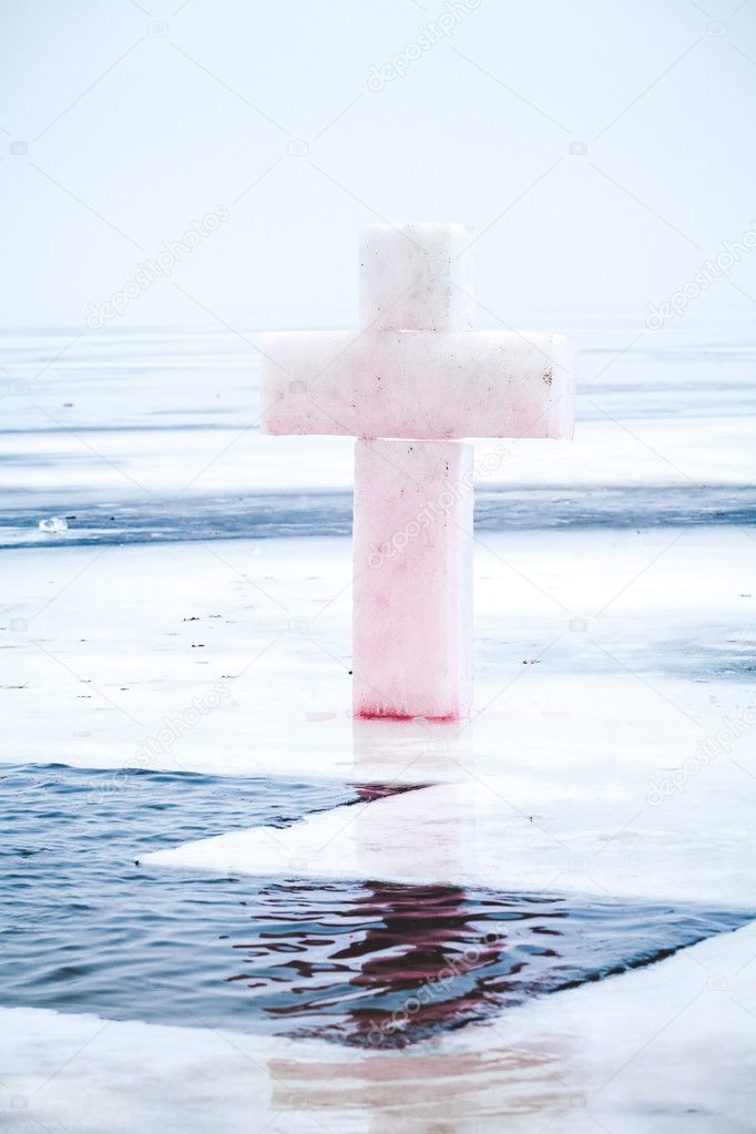 Cross made of ice in front of him on the frozen pond hole winter cloudy da