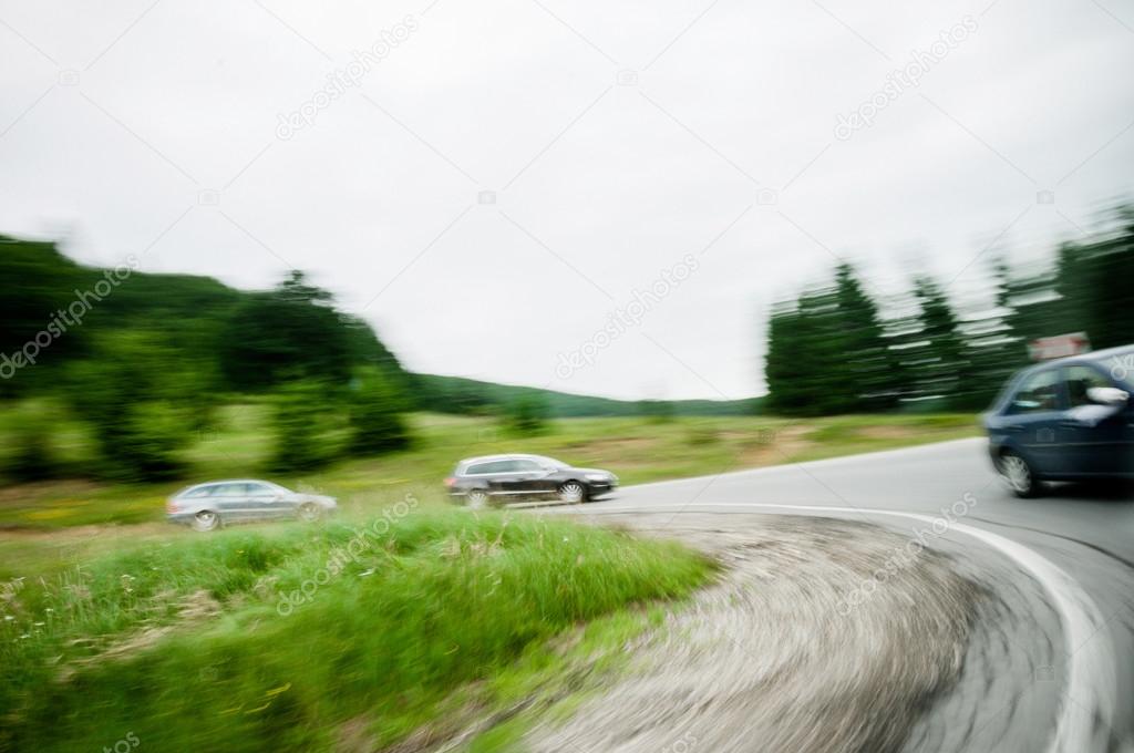 Three cars driving on a bend on a country highway road
