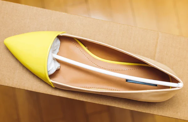 Yellow leather shoe placed on cardboard box — Stock Photo, Image