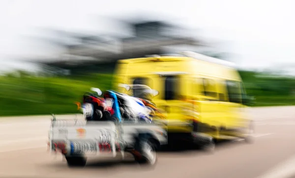 Vista desenfocada de la furgoneta que lleva un remolque de motocicleta deportiva —  Fotos de Stock