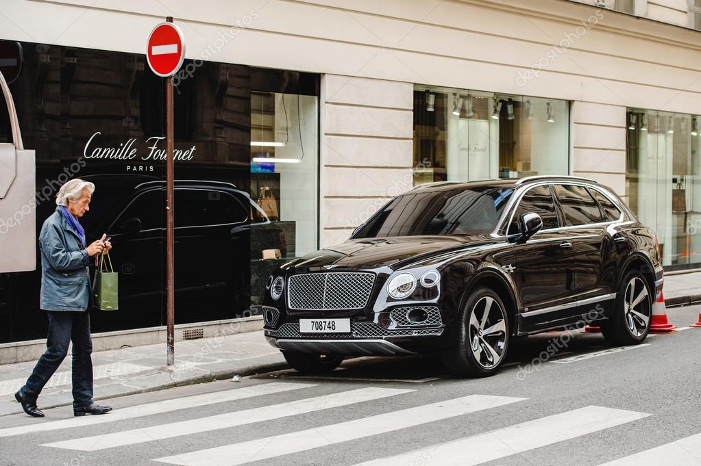 PARIS, FRANCE - MAY 21, 2016: Man taking photo of the luxury Bentley Bentayga Hybrid SUV on the streets of Paris, France