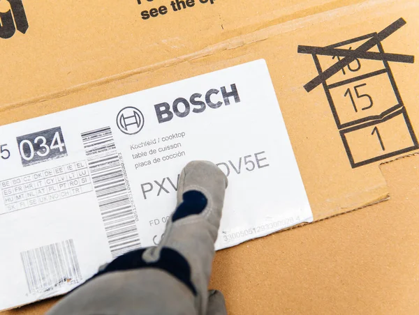 Мужской инсталлятор указывает на картонную коробку Bosch Cooktop — стоковое фото