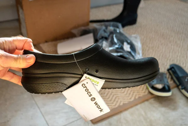 POV male hand holding Crocs at work professional rubber shoes — Stock Photo, Image