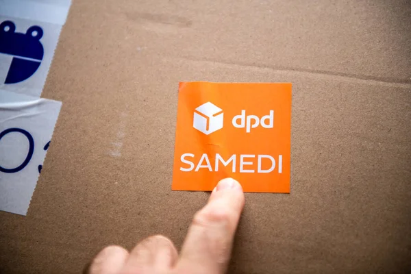Paris, Frankreich - 14. Oktober 2020: Pov männliche Hand zeigt auf den Pappkarton-Aufkleber mit DPD-Schriftzug und Text samedi übersetzt als Samstagszustellung — Stockbild Samstag Paketzustellung durch DPD — Stockfoto