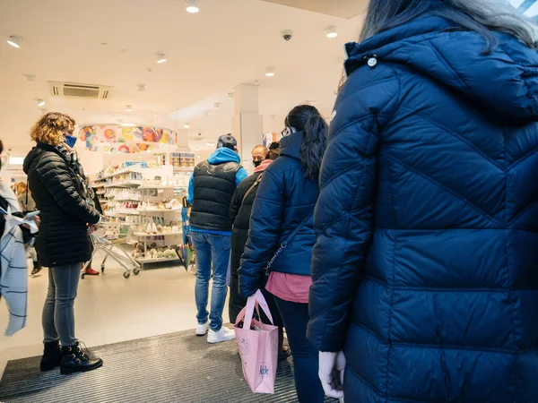 Pessoas com máscaras esperando em uma fila dentro da loja DM — Fotografia de Stock