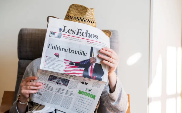 Woman reading in living room the latest Les Echos newspaper featuring on cover page the final day of election for U.S — Stock Photo, Image