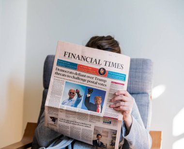 Financial times being read by woman in living room FT the latest newspaper featuring on cover page us elections clipart