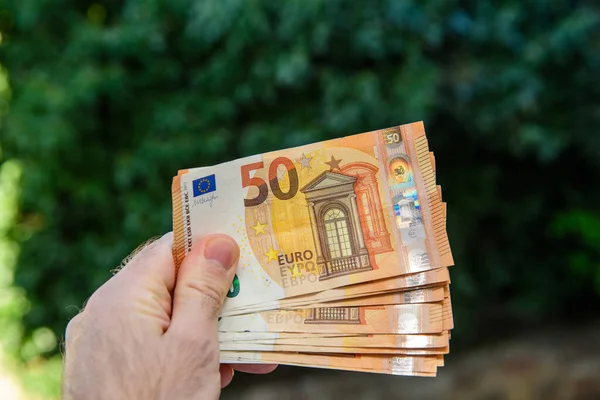 Holding multiple 50 euro bills against green background — Stock Photo, Image