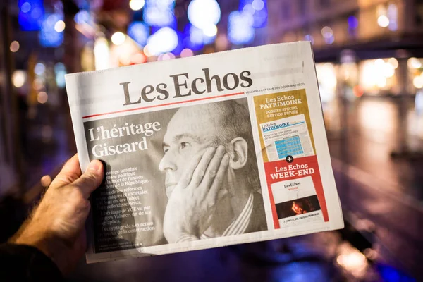 Hombre sosteniendo el periódico Les Echos en el quiosco de prensa francés anunciando la muerte de Valery Giscard dEstaing —  Fotos de Stock