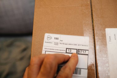 Hollanda 'daki Post NL posta paketini işaret eden erkek elinin yakın çekim makro görüntüsü bir imza karşılığında teslim edilecek metinle