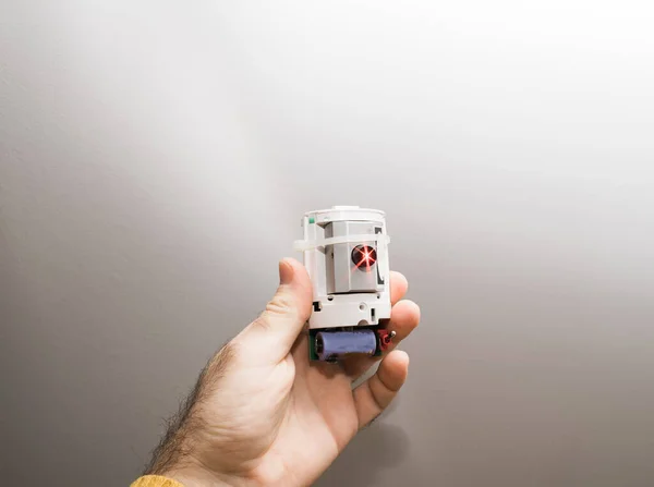 Αρσενικό χέρι κρατώντας φουτουριστικό σπίτι ασφάλεια λέιζερ beamer συσκευή συναγερμού ασφαλείας με κόκκινο φως λέιζερ σε λειτουργία για την ανίχνευση εισβολείς και κλοπές — Φωτογραφία Αρχείου