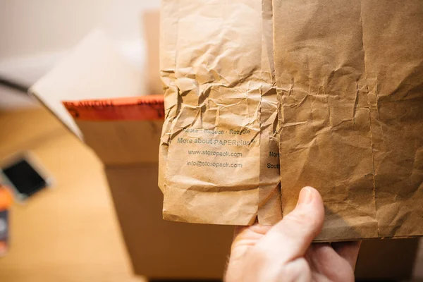 POV мужская рука, упаковывающая бумагу Storopack plus для посылок с лозунгами Повторное использование, Утилизация и Переработка — стоковое фото