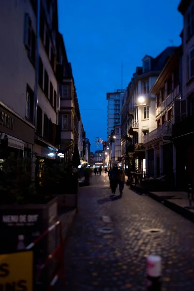 Perspective view over tiny cozy French street with pedestrians walking at dusk on the first day of the year wearing masks - tilt-shift lens focus — Stock Photo, Image