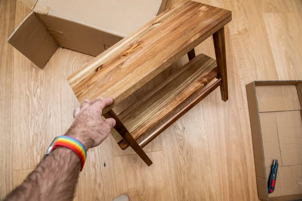 Мужская рука держит новую натуральную роскошную деревянную скамейку во время процесса распаковки — стоковое фото