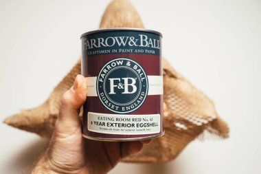 POV erkek eli, Farrow ve Ball Dorset İngiltere Yemek Odası 'nın beyaz ve kıvrımlı kağıt arka plan paketinde tecrit edilmiş. Metal ve ahşap için dış yumurta kabuğu boyası