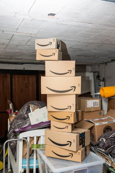 Multiple parcels from Amazon online internet retailer arranged in a tower in a large garage with multiple messy cardboards — Stock Photo, Image