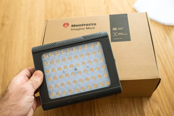 POV samec ruční vybalení nové Manfrotto LED Light Lykos 2.0, 2 v 1 voděodolné s Bluetooth balení v pozadí — Stock fotografie