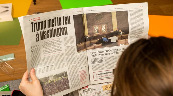 Mujer leyendo en sofá periódico francés Liberation interiour page show storming of the U.S. Capitol — Foto de Stock