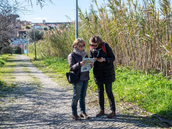 Yetişkin ve kıdemli bir kadın Lizbon haritasında yeşil bambu parkının yanındaki kaldırım taşı kırsal yolda bir adres bulmaya yardım ediyor. — Stok fotoğraf