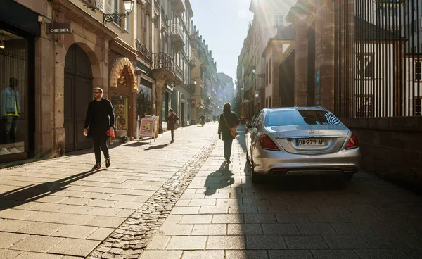 Fußgängerzone mit wenigen Menschen zu Fuß in der Nähe von Luxus-Mercedes-Benz Limousine Auto geparkt in der Nähe von hohen Metalltor — Stockfoto